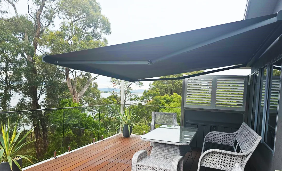 Folding arm awning extended over a timber deck with outdoor seating