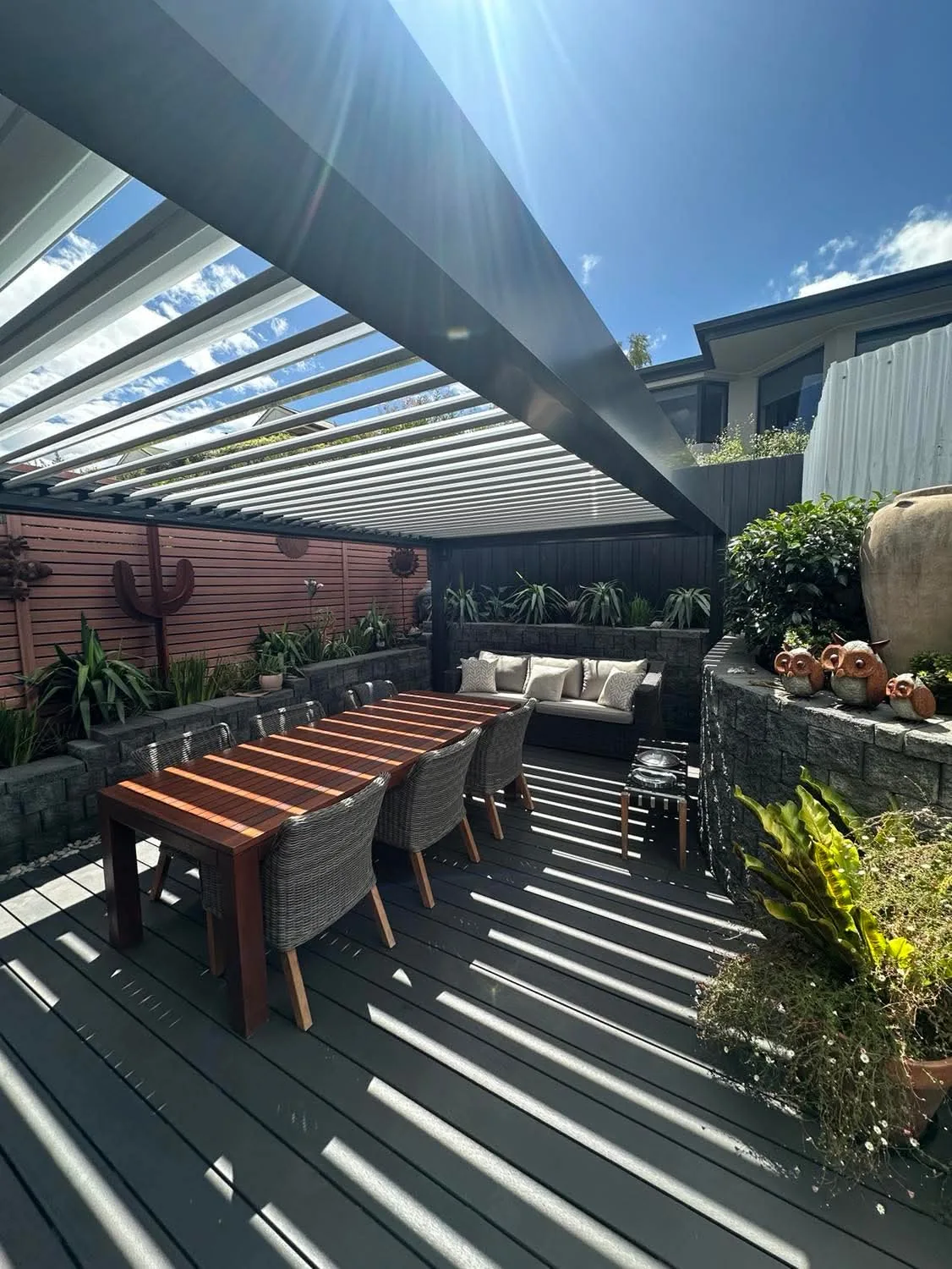 Sun striking the open louvres of a Lumex louvre roof above a timber deck
