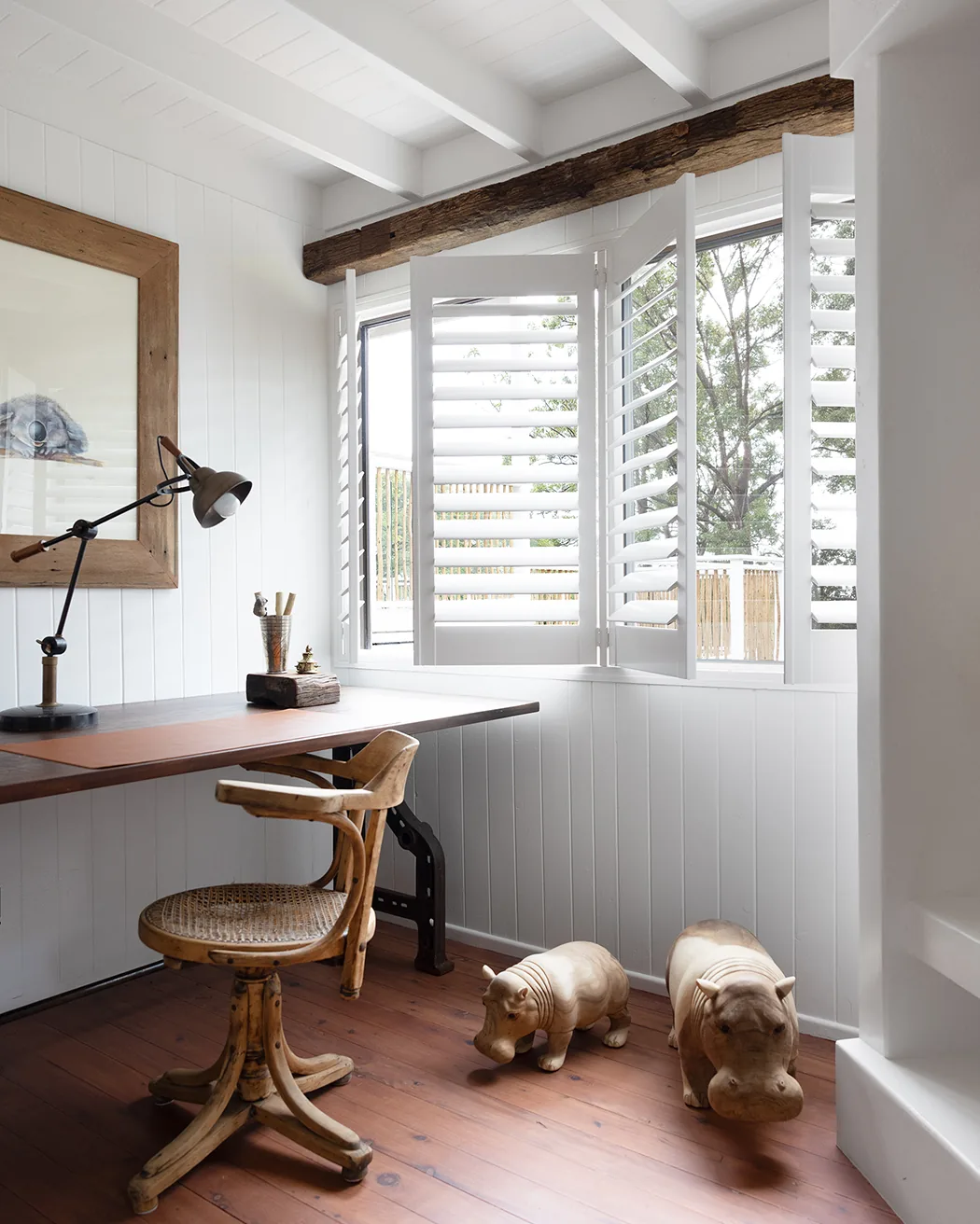 Plantation shutters folded back beside a timber study nook